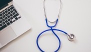 Stethoscope on a table next to a laptop