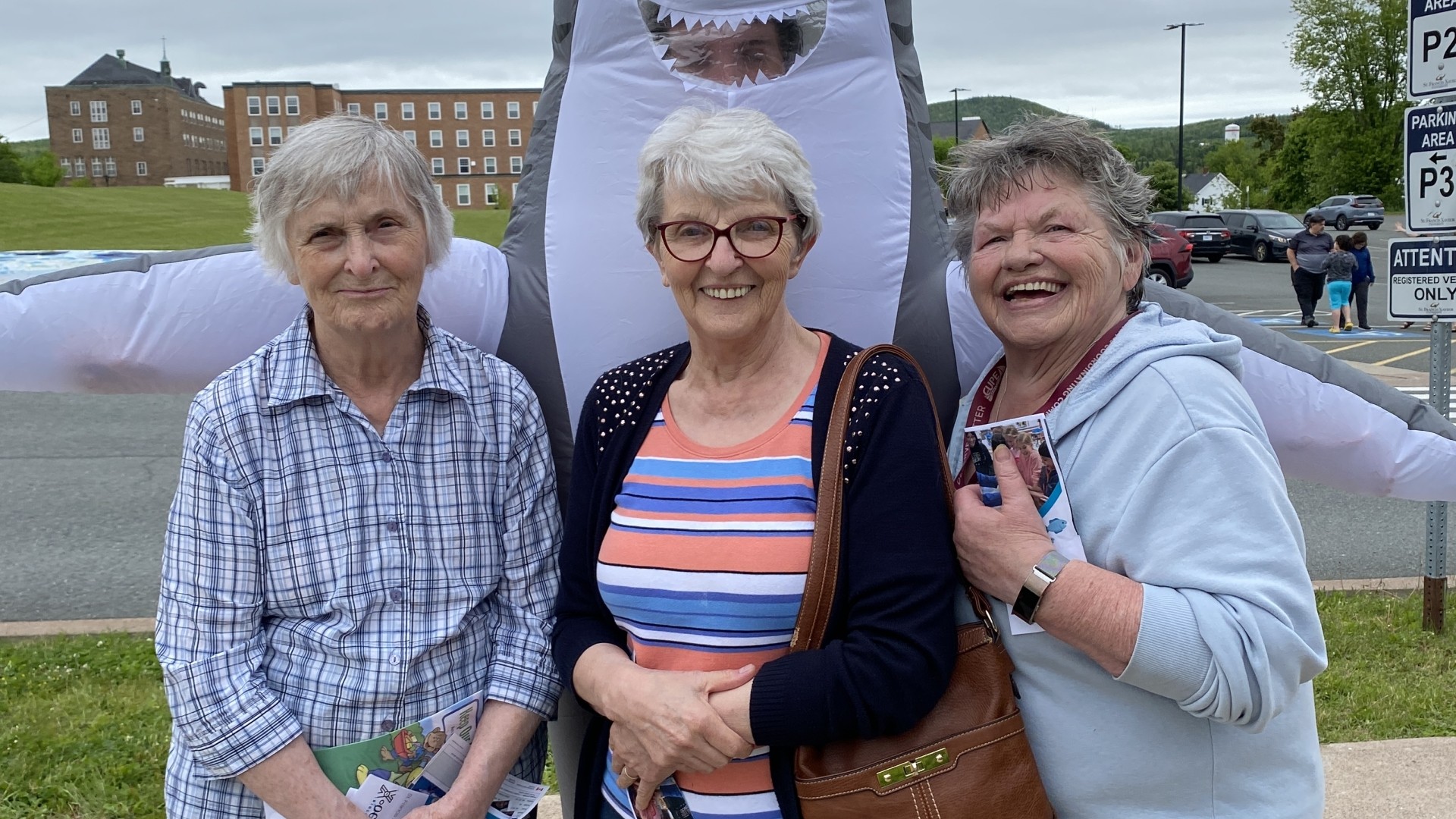 A shark mascot and visitors at World Oceans Day 2024