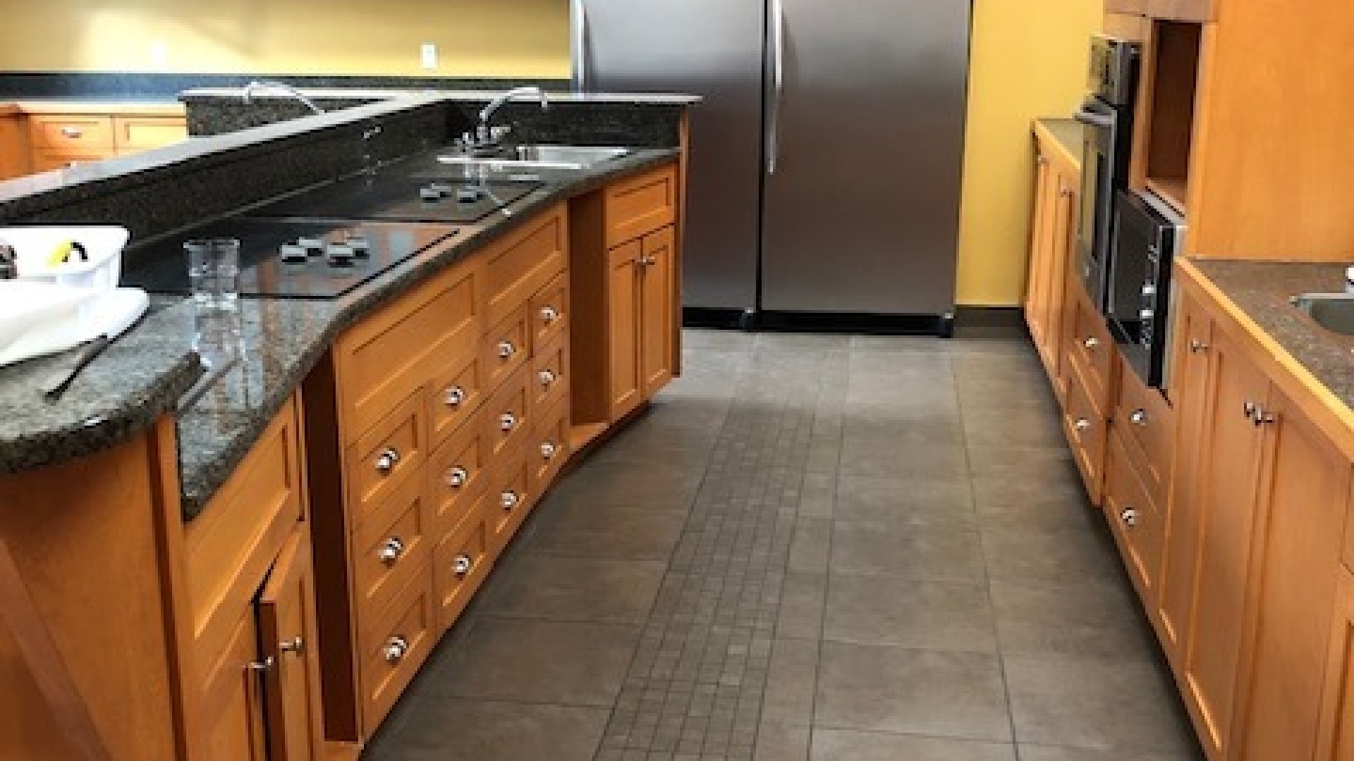 Kitchen with a large fridge and multiple counter top stoves.