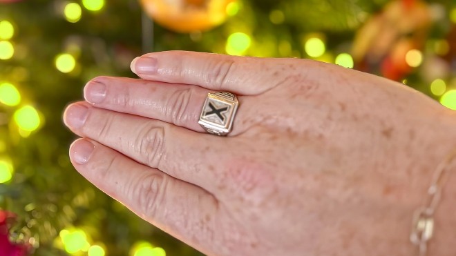 Becky displays her lost-and-found X-Ring on her hand in front of a Christmas tree