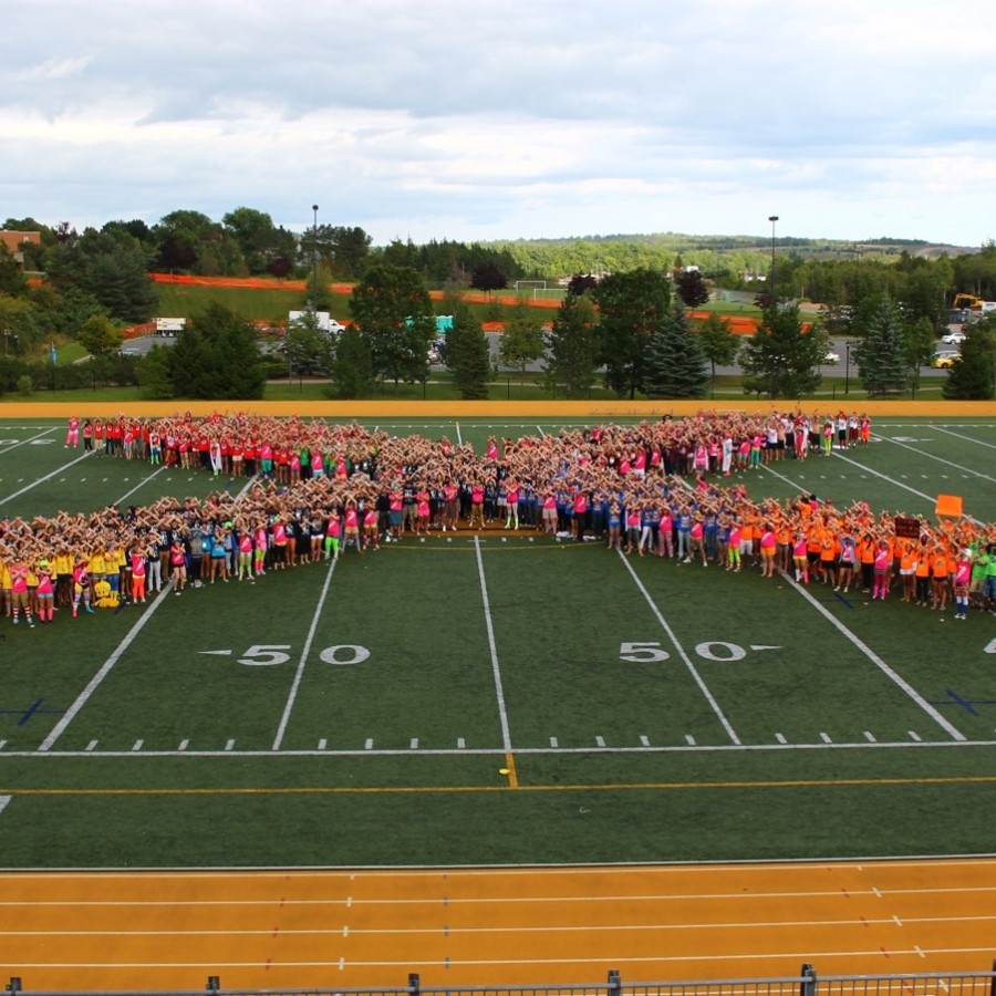 View from bleachers of students on the StFX football field lined up to form an X.