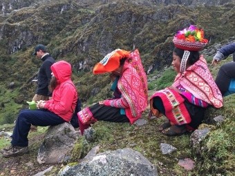 2 people in indigenous Peruvian clothes one person in raincoat