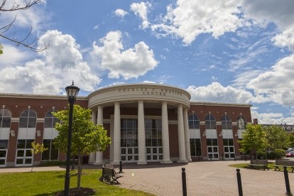 Exterior of the Charles V. Keating Centre main entrance on a sunny day with some clouds.