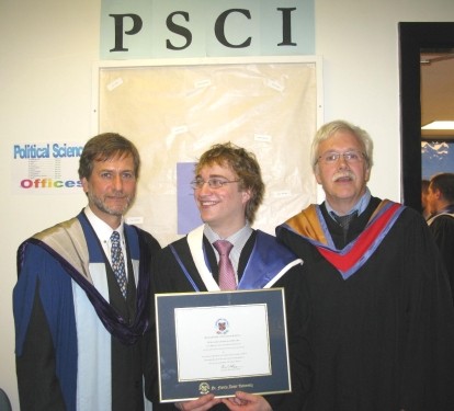 One graduated student showing his diploma, next to 2 men.